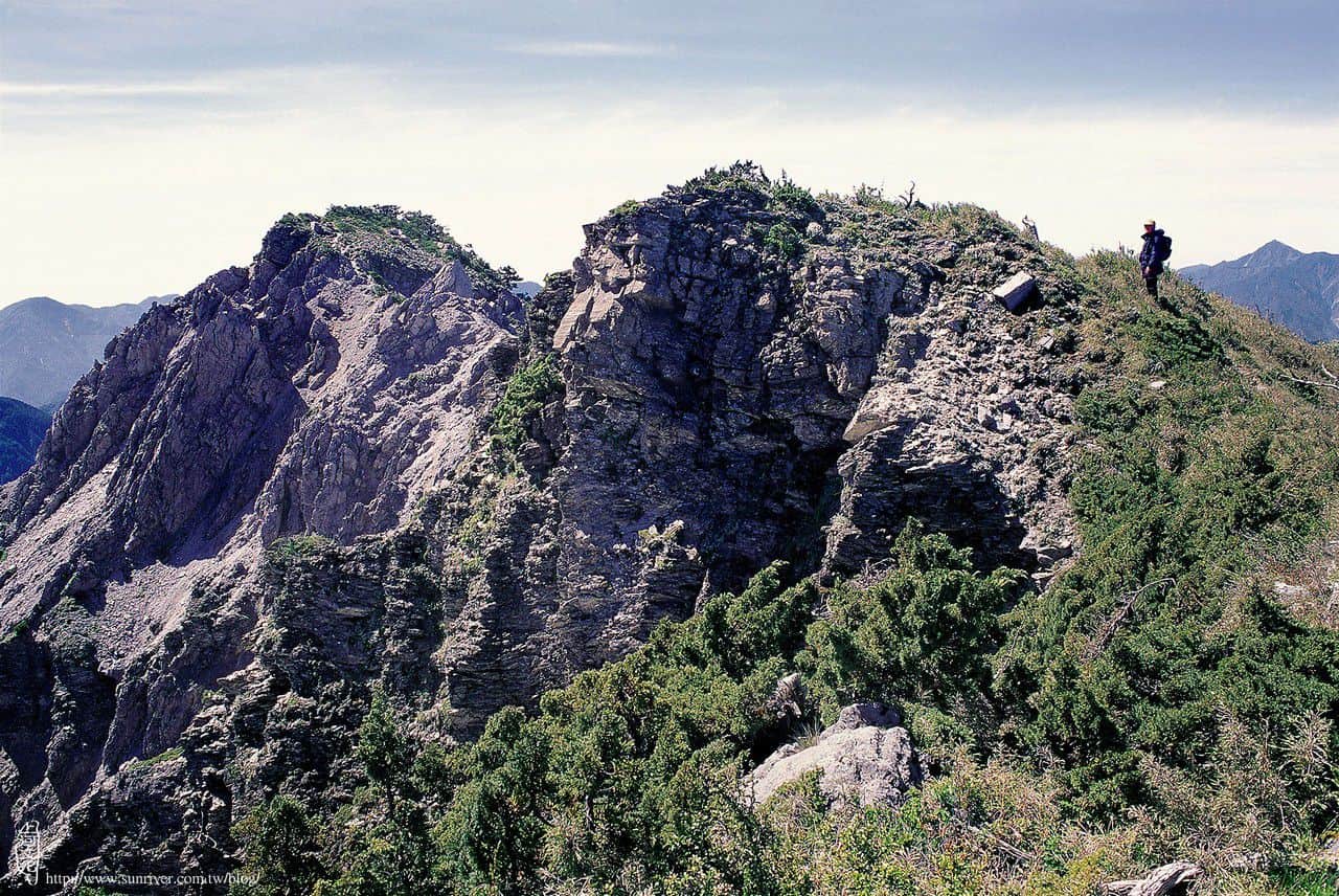 巴巴山半面是傾降的箭竹草坡，半面是山冢崒崩的大斷崖。 圖左側向東尖突的峰頭即是巴巴山。 攝影∕蕭官誠　地點∕巴巴山前